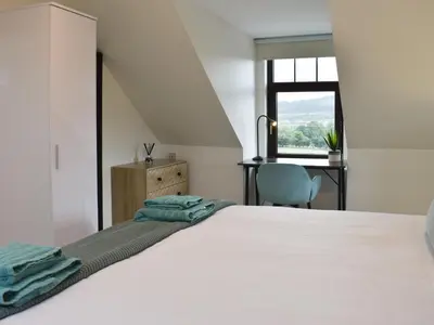 a bedroom with a bed and a desk and a window at Park House in Blackwaterfoot