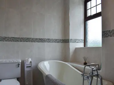 a bathroom with a bath tub and a toilet at Park House in Blackwaterfoot
