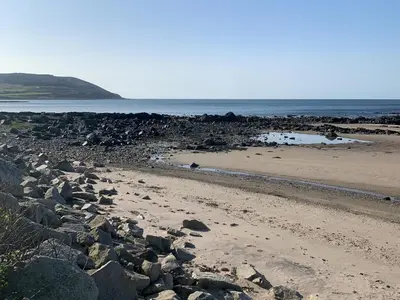 a sandy beach with rocks and the ocean at Park House in Blackwaterfoot