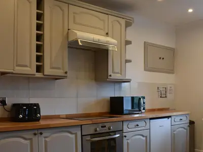 a kitchen with white cabinets and a microwave at Park House in Blackwaterfoot