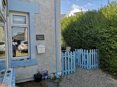 a white picket fence next to a house at Redhurst Cottage in Lamlash