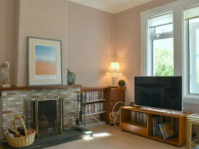 a living room with a fireplace and a flat screen tv at Redhurst Cottage in Lamlash