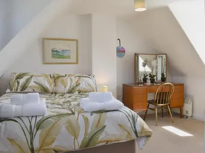 a bedroom with a bed with a dresser and a chair at Redhurst Cottage in Lamlash