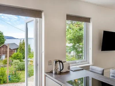 a kitchen with a desk and a large window at Sea Breeze Cottage in Lochranza