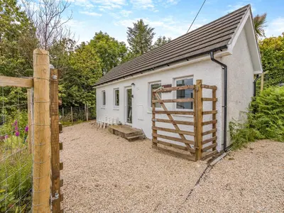 a small white building with a fence and a gate at Sea Breeze Cottage in Lochranza