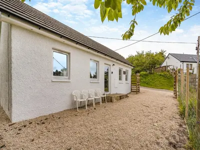 a house with three chairs sitting outside of it at Sea Breeze Cottage in Lochranza