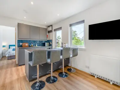 a kitchen with a bar with chairs and a flat screen tv at Sea Breeze Cottage in Lochranza