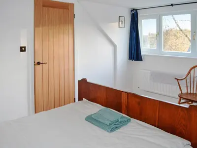 a bedroom with a bed with a wooden headboard and a window at Old Steading in Brodick