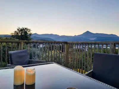 a table and chairs on a balcony with mountains at An Cala in Brodick