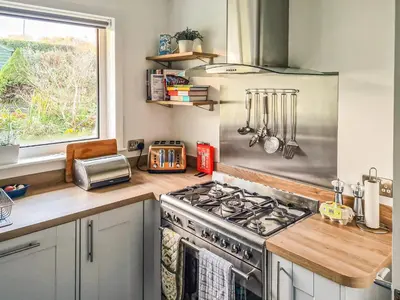 a kitchen with a stove and a window at An Cala in Brodick