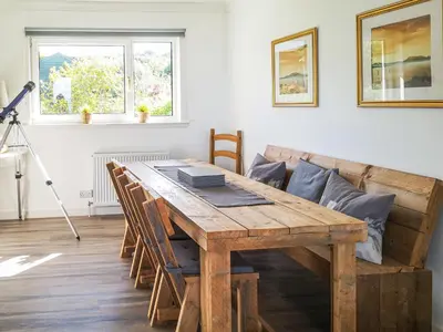 a dining room with a wooden table and a couch at An Cala in Brodick