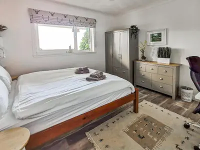 a bedroom with a large bed and a window at An Cala in Brodick