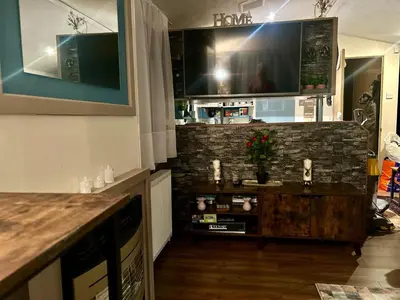 a living room with a tv on a brick wall at 23 Chestnut Grove in Kirkcolm