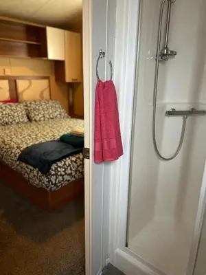 a bathroom with a shower and a bedroom with a bed at 23 Chestnut Grove in Kirkcolm