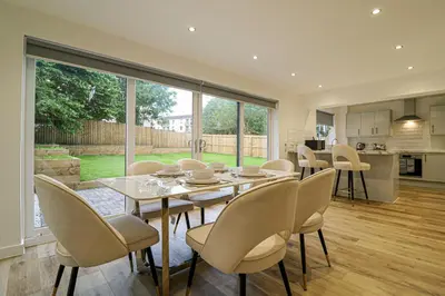 a dining room with a table and chairs and a kitchen at Wyndford Riverside House in Glasgow