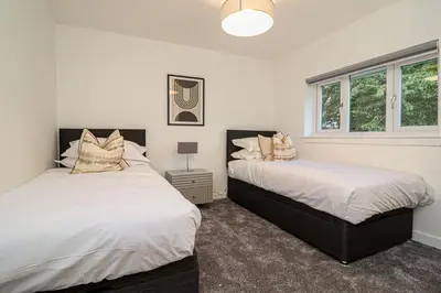 a bedroom with two beds and a window at Wyndford Riverside House in Glasgow