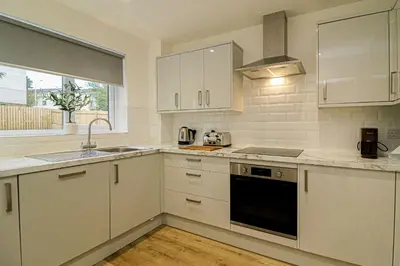 a kitchen with white cabinets and a sink at Wyndford Riverside House in Glasgow