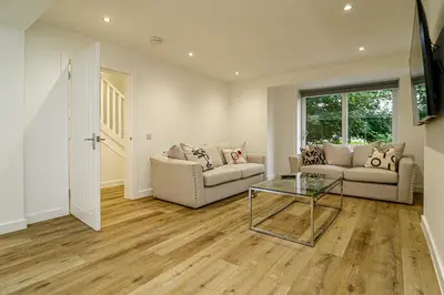 a living room with two couches and a glass table at Wyndford Riverside House in Glasgow