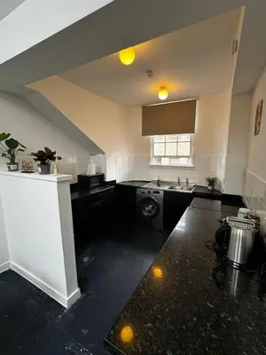 a kitchen with black counters and a sink and a stove at Victoria Street View Flat in Edinburgh EB10 in Edinburgh