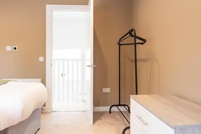 a bedroom with a bed and a dresser and a door at Moncrieff House in Livingston