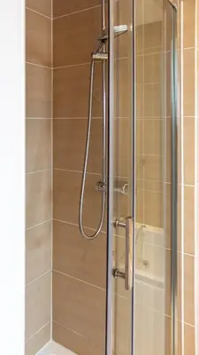 a shower with a glass door in a bathroom at Moncrieff House in Livingston
