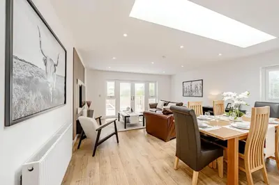 a dining room and living room with a table and chairs at Cowden Coorie in Fife