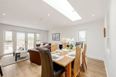 a dining room and living room with a table and chairs at Cowden Coorie in Fife