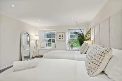 two white beds in a white room with windows at Timeless 5 bed Duplex Flat in Glasgow