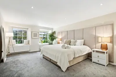 a white bedroom with a large bed and a window at Timeless 5 bed Duplex Flat in Glasgow