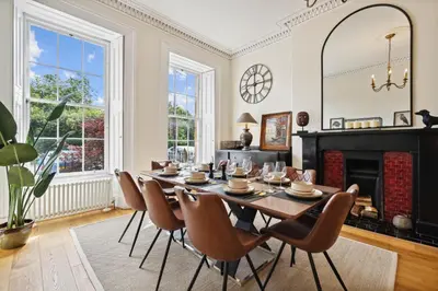 a dining room with a table and chairs and a fireplace at Timeless 5 bed Duplex Flat in Glasgow