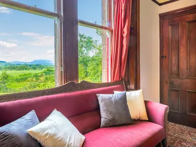 a red couch in a room with a large window at Burncliff in Blackwaterfoot