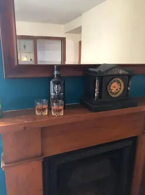 a fireplace with two glasses and a clock on it at House in Drymen Village with free local health club access in Glasgow