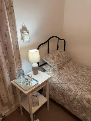 a bedroom with a bed and a table with a lamp at Single room with beautiful garden in Edinburgh