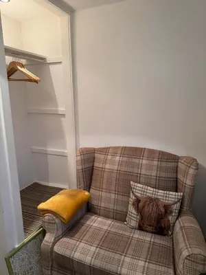 a dog sitting on a couch with a pillow at Single room with beautiful garden in Edinburgh