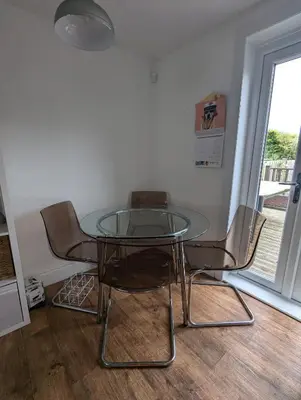 a glass table and chairs in a room with a window at Single room with beautiful garden in Edinburgh