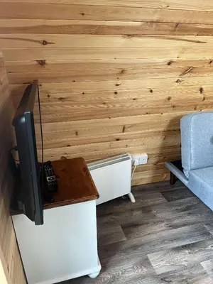 a room with a tv and a couch and a table at Penny gown farm pod in Campbeltown