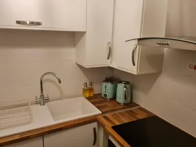a kitchen with white cabinets and a sink at 223 Websters land - stunning castle view in Edinburgh