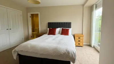 a bedroom with a bed with white sheets and red pillows at 19 Snowdon Apartment in Stirling