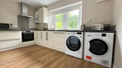 a kitchen with white cabinets and a washer and dryer at 19 Snowdon Apartment in Stirling