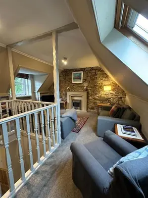 a living room with a couch and a staircase at Loch Lomond 2 Bedroom Apartment in Tarbet