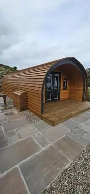 a small wooden building with a bench on a patio at Kintyre Glamping Pods in Campbeltown
