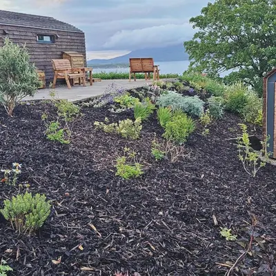 a garden with two benches and a table and benches at Kintyre Glamping Pods in Campbeltown