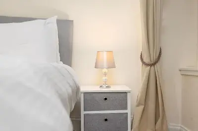 a bed with a night stand with a lamp on it at Two Bedroom Apartment-Central Edinburgh-Old Town-licensed in Edinburgh