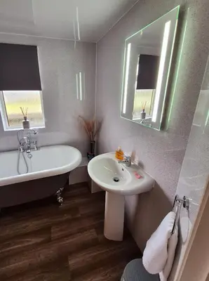 a bathroom with a tub and a sink and a bath tub at Top Lodge in Newton Stewart