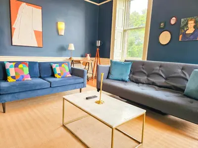 a living room with blue couches and a table at Spacious 2 Bedroom Apartment in the heart of New Town in Edinburgh