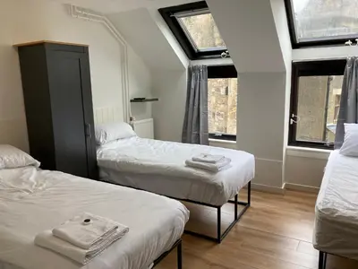 a room with two beds and two windows at Linlithgow Hostel in Linlithgow