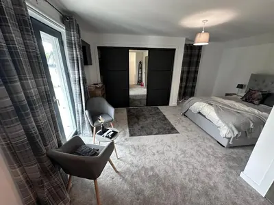 a bedroom with a bed and a chair and a window at The Orchard Suite in Dalserf