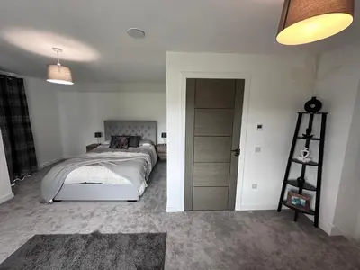 a bedroom with a bed and a ladder next to a door at The Orchard Suite in Dalserf