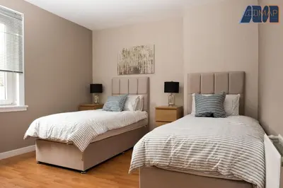 a bedroom with two beds and a window at Paisley Haven on Renfrew Road in Merksworth