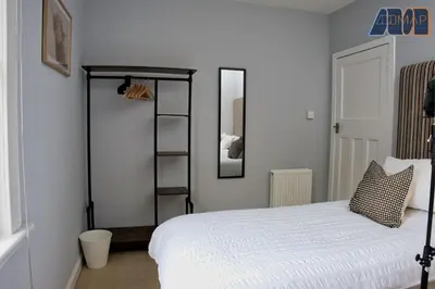 a bedroom with a white bed and a shelf at Paisley Haven on Renfrew Road in Merksworth